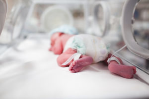 Newborn lying in an incubator in a neonatal intensive care unit (NICU)