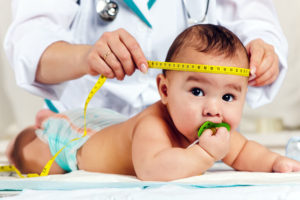 A doctor checking the size of a baby's head with measuring tape