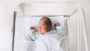 A newborn baby sleeping in a hospital crib.