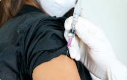 A medical professional administers a birth control shot to a women's arm using a syringe.