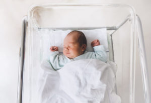 A newborn baby sleeping in a hospital crib 