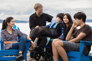 Members of a special needs support group relax on the deck of a lake.