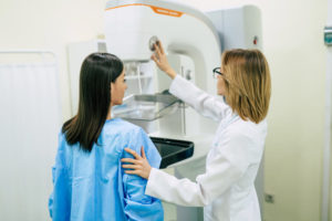 Woman standing in front of a mammography machine with her doctor 