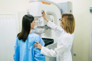 Woman standing in front of a mammography machine with her doctor