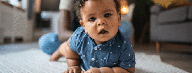 A baby commando crawls on their stomach across the floor.