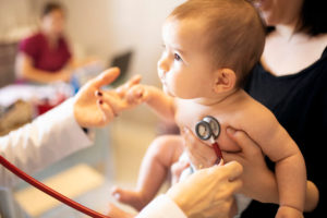 A doctor places a stethoscope on a baby's chest