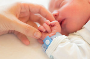 newborn baby holding mom's finger
