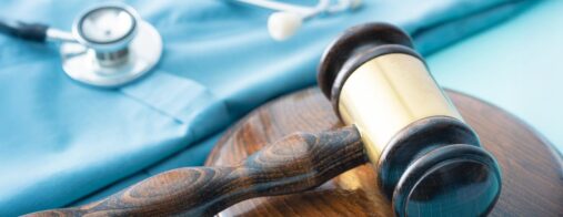 A gavel and stethoscope sit alongside a pair or teal medical scrubs
