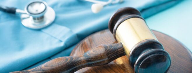 A gavel and stethoscope sit alongside a pair or teal medical scrubs