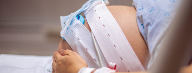 Mother holds pregnant belly in hospital