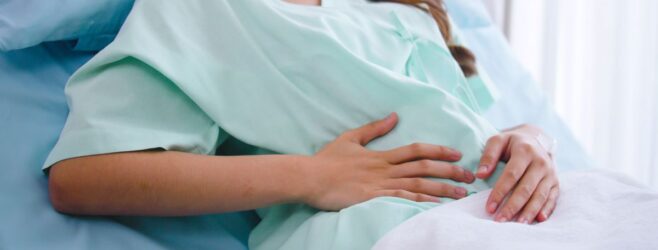 A woman with brown hair lays back in a hospital chair, presumably in labor.
