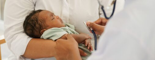 A health care provider uses a stethoscope to examine a newborn
