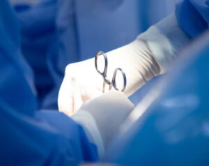 Closeup of hands wearing surgical gloves and using forceps during a medical procedure.