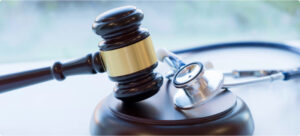A gavel and stethoscope rest together on a block.