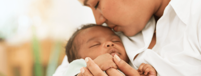 Mother gently holding and kissing her newborn baby, showing close bonding and care after birth.