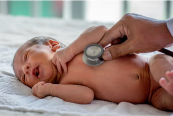 A doctor uses a stethoscope to check a newborn's heart.