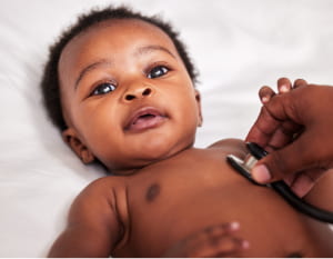 A medical professional uses a stethoscope to listen to a baby's heart.
