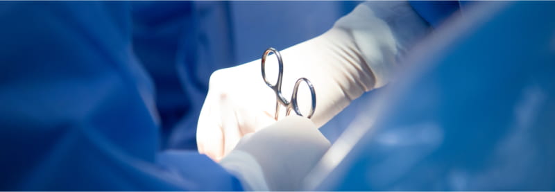 Closeup of doctors hands wearing latex gloves and using forceps.