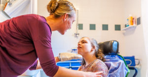 a nurse helps a girl with cerebral palsy