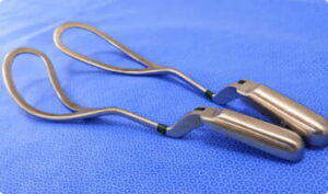 Close-up of obstetrical forceps, medical tools used in assisted delivery, against a sterile background.