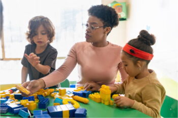 A special education teacher plays with building blocks with two young students
